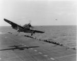 SB2C Helldiver getting a wave-off from USS Bunker Hill, 1943. Note Helldiver in the distance with wheels up but flaps down, apparently preparing for a water landing.
