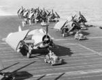 Shipboard aircraft tugs moving a TBM-1C Avenger torpedo bomber and F6F Hellcat fighters aboard the Fleet Carrier USS Lexington (Essex-class), 1945.