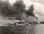 Damaged PBY Catalinas on the seaplane ramp of Ford Island, Pearl Harbor, Oahu, Hawaii, Dec 7, 1941. White smoke from burning hangars and black smoke from burning battleships is also visible.