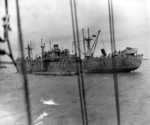 Liberty ship unloading two CCKW trucks and other supplies onto a Rhino cargo barge off the Normandy beaches, Jun 1944.