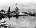 Destroyer USS Shaw with its bow blown away still floats in the now sunken Floating Drydock YFD-2 in Pearl Harbor, Oahu, Hawaii, Dec 8, 1941. USS Curtiss is on the left and Battleship Row in the distance.