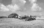 P-47 Thunderbolts of the 19th Fighter Squadron share the airfield with Marine Corps TBM Avengers Isely Field on Saipan, Mariana Islands, mid 1944. Note incomplete Japanese hangar.