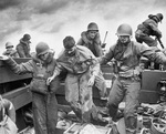 US Coast Guardsmen assisting a wounded Marine into an LCVP after the Marine’s LVT sustained a direct hit while heading to the landing beaches on Iwo Jima, Feb 18, 1945.