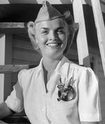 WASP pilot Anne Armstrong McClellan showing off the WASP dress white uniform blouse and pin showing the WASP mascot, Fifinella (designed by Walt Disney and used by the WASPs with permission), 1944.