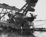 Badly damaged USS Arizona foremast structure, bridge, and top of turret number 2 in Pearl Harbor, Hawaii, 17 Feb 1942. Note floating crane YD-25 at left