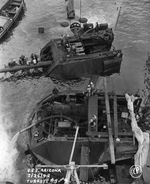 Salvage work continuing on the sunken battleship USS Arizona in Pearl Harbor, Hawaii, 25 Feb 1942. Note Arizona’s two after main turrets being pumped out and disassembled.