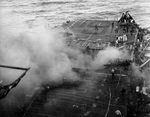 Crews aboard USS Enterprise controlling fires from a Japanese bomb that blew the forward elevator completely out of the ship, off Kyushu, Japan, 14 May 1945.