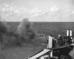 Smoke pouring through a large hole in the Ticonderoga’s flight deck from fires after a special attack aircraft crashed through the deck off Formosa (Taiwan) on 21 Jan 1945