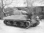 Sgt Dee Perry of the 10th Armored Division applying winter paint to his M4 Sherman tank in Belgium, 12 Jan 1945.