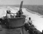 Combat training exercises aboard PT-107, an 80-foor Elco torpedo boat, circa 1942. Note twin Browning M2 .50 caliber machine guns and sailor astride Mk 6 depth charge.