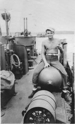 Torpedoman Second class Richard Malecki sitting astride a Mark XIII aerial torpedo aboard PT-184, May 1945. Note Mark 6 Depth Charge in the foreground and a twin Browning .50 caliber machine gun mount in the background.