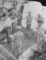 Sergeant Bob Briggs, Major Francis Hegarty, Colonel Smith, Major George V. Campbell, Lieutenant General Joseph Stilwell, Dan Songh, Corporal William Brend, and others in a chow line, India, Mar 1944