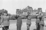 Allied officers during a parade in Berlin, Germany, 6 May 1946; note ruins of Reichstag building in background