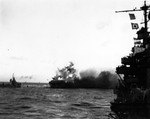 As her own torpedo warheads explode aboard USS Lexington, an aircraft is blown over the side in the Battle of the Coral Sea, 8 May 1942 at 1727 hours local time. Destroyer Hammann is backing down at left.