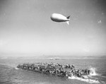 A Rhino barge loaded with men and equipment during exercises in southern England, United Kingdom, prior to the Normandy invasion, May 1944. Note the barge’s two large outboard motors and tethered barrage balloon.