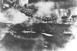 Japanese aerial photograph of the overturned USS Utah, sunk by torpedoes in the Japanese air attack on Pearl Harbor, Hawaii, 7 Dec 1941. Cruisers Detroit and Raleigh can be seen at left and USS Tangier at right.