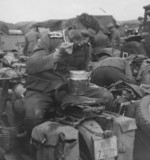 German soldier eating a meal in the field atop a BMW R12 motorcycle, date unknown