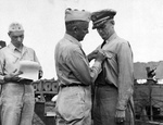 Captain Arleigh Burke receiving the Navy Cross from Rear Admiral Arthur Merrill aboard the destroyer Charles Ausburne in Purvis Bay, Florida Island, Solomons, 30 Jan 1944.