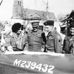 Field Marshal Bernard Montgomery, Major General Brian Horrocks, and Major R.P.P. Smyly examining a map on the hood (bonnet) of a staff car in the village of Marienbaum, Germany, 25 Mar 1945.