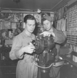 Two bombsight technicians working on a Lucas Harold built Norden bombsight on a calibration stand, presumably in the Burma Theater circa 1944. Note the “training material” on the wall behind the technicians.