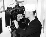 United States Navy Boatswain aboard USS Saratoga pipes a signal over the ship’s speaker system, circa 1942.