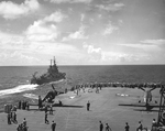 Forward flight deck of USS Ticonderoga with two Grumman F6F-5 Hellcats spotted and a cruiser, either USS Pasadena or USS Springfield, off the port bow, Jul 1945 as they steamed from Leyte toward Japan.