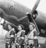 The first WAAF orderlies Leading Aircraftwoman Myra Roberts, Corporal Lydia Alford, and Leading Aircraftwoman Edna Birbeck selected to fly on air ambulance duties to France posing before a Dakota Mk III of No. 233 Squadron RAF at B-2 Bazenville Advanced Landing Ground, Normandie, France, mid-Jun 1944