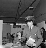 Leading Aircraftwoman Vera Blackbee holding documents given by a Ministry of Labour representative, WAAF Demobilisation Centre, RAF Wythall, Worcestershire, England, United Kingdom, 1945