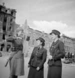 WAAFs Section Officer P. Hack (center) and Section Officer B. Hampson with a Soviet Red Army traffic controller, near the Brandenburger Tor on the Unter den Linden, Berlin, Germany, 1945