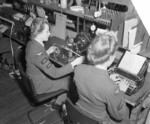 A WAAF member transposing a plain language message into perforated morse tape while the other threaded the tape into a high-speed transmitter, Headquarters No. 60 (Signals) Group, RAF Leighton Buzzard, Bedfordshire, England, United Kingdom, date unknown