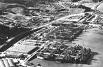 Aerial view of Marinship yard with six ways with tanker hulls under construction, eight tankers at the fitting out docks, and worker housing at the top, Sausalito, California, United States, 1943.