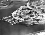 Overhead view of the Finger Piers at the Pearl Harbor Submarine Base, Pearl Harbor, Hawaii, circa 1932. Note the Fleet Headquarters building, the submarine escape training tower, and the barracks ship, the ex-USS Chicago