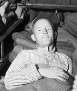 William Joyce in an ambulance under armed guard with a thigh gunshot wound, Flensburg, Germany, 29 May 1945, photo 3 of 3
