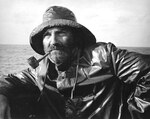 Commanding officer of Gato-class submarine USS Silversides Lieutenant Commander C.C. Burlingame on the bridge in foul weather gear with a corn-cob pipe, sometime in 1942.