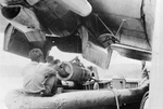 A Mark XIII aerial torpedo with wooden shroud rings fore and aft being loaded from a boat into the starboard bomb bay (in the engine nacelle) of a PBM Mariner patrol aircraft, probably 1945 in the Pacific.