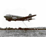C-47 Skytrain aircraft recovering a CG-4A glider, Normandy, France, 23 Jun 1944; note hooked tow line from C-47 getting ready to hook onto a net connected to glider