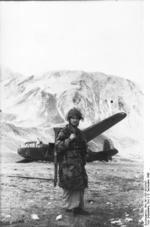 German glider trooper posing with a FG 42 rifle before a DFS 230 C-1 glider, Gran Sasso, Italy, 12 Sep 1943