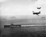 SB2C Helldivers flying over USS Essex during the Okinawa campaign, May 1945; USS Bunker Hill, USS Langley, and other vessels in background