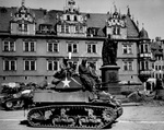US Army African-American crew of the 761st Tank Battalion on a M5A1 Stuart light tank in Coburg, Bayreuth, Germany, 25 Apr 1945. Note white flags hanging from upper palace windows. Also note evidence that those windows have been machine gunned.