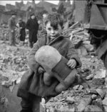 Abandoned boy holding a stuffed toy animal amid ruins following German aerial bombing of London, England, United Kingdom, 1940