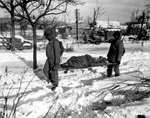 Two US Army African-American soldiers carrying the body of another American soldier near Malmédy, Belgium, circa 17 Dec 1944