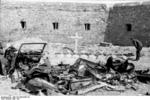 Temporary grave for a soldier amidst destroyed cars and damaged buildings, Calais, France, May 1940