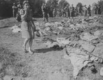 A German woman covering her nose and mouth as she walked by the 800 exhumed bodies of forced laborers murdered by SS men, near Nammering, Germany, 17 May 1945