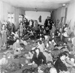Women and children, former inmates of Bergen-Belsen Concentration Camp, huddled together in a large room after liberation, Germany, 17-18 Apr 1945