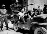 German prisoner wearing civilian clothes sitting in jeep at south gate of the walled city of Lucca, Italy, circa Sep 1944