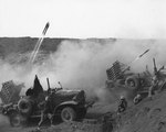 US Marine rocket-launching trucks in action on Iwo Jima, Japan, 28 Feb 1945; note Mk 7 rocket launcher firing 4.5-inch beach barrage rockets