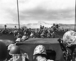 Men of the US 4th Marines rushing out of their landing craft for Iwo Jima landing beach, 19 Feb 1945, photo 1 of 2; note LVT burning in right center