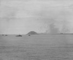 Minesweepers worked the waters off Iwo Jima before the invasion, 17-18 Feb 1945; note the anti-aircraft bursts above the island and a burning aircraft close to the ground on the right