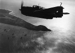 US Navy TBM-3 Avenger over Iwo Jima, Japan, Mar 1945; note Mount Suribachi in center of photo and Allied ships to northwest (left)