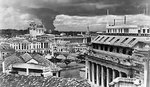 A column of smoke from burning oil tanks rising above the deserted streets of Singapore, Feb 1942; note General Post Office in foreground, now Fullerton Hotel Singapore